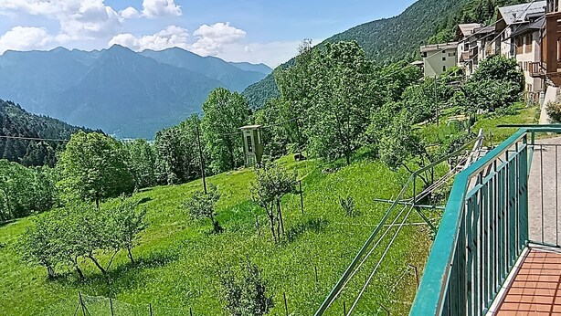 Une vue sur une colline, avec des bâtiments, un ciel dégagé et des montagnes en arrière-plan.