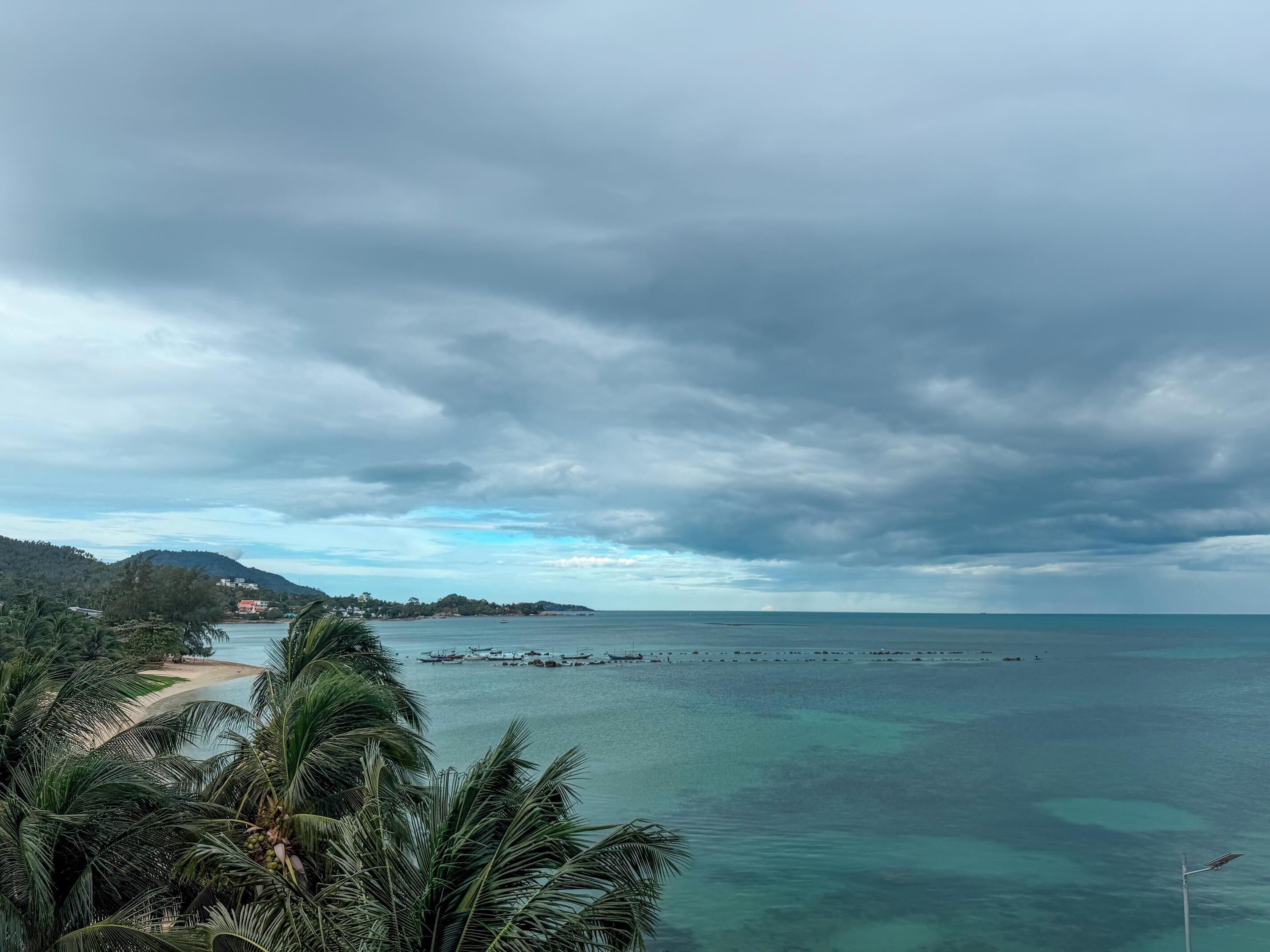 A coastal view with a beach, clear water, and a cloudy sky.