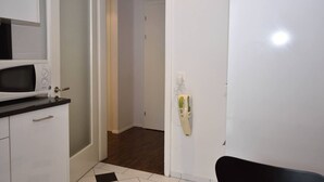 A kitchen with a microwave, a refrigerator, and a black countertop. There is a white door leading to another room. - Charming studio near lake - Flower 42 (Zürich)
