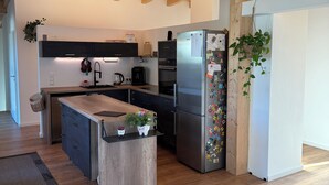 Eine moderne Küche mit Holzbalken, einer zentralen Kochinsel und einem Kühlschrank mit Magneten.