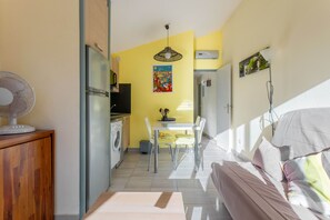 Ein kompakter Wohnbereich mit Küchenzeile, Essbereich und Bett.