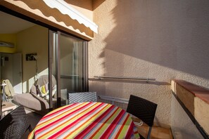 Ein sonnendurchflutetes Zimmer mit einem Bett, einem Sessel, einem Tisch und einem Fenster.