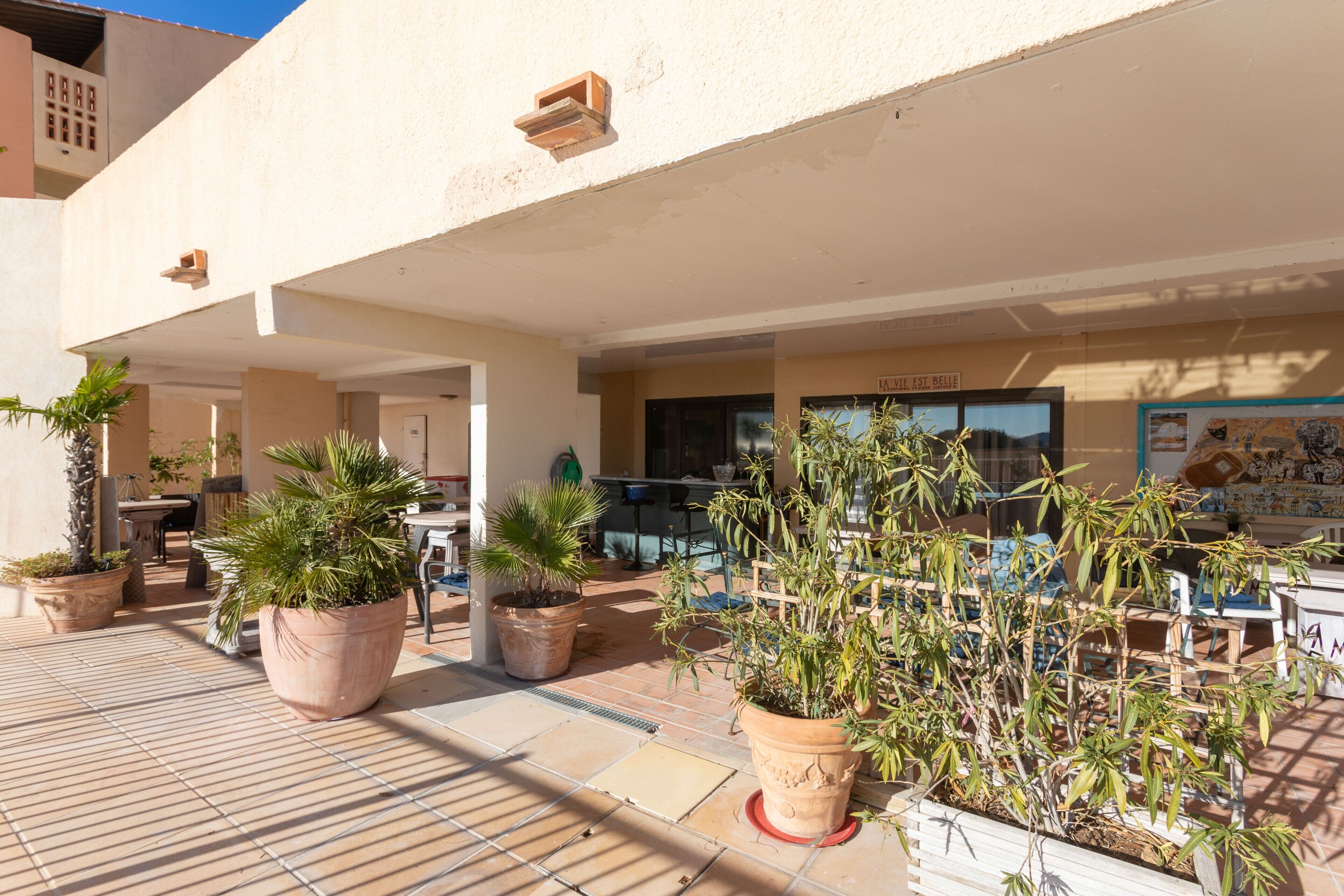 An outdoor patio area with potted plants, outdoor seating, and a building entrance.