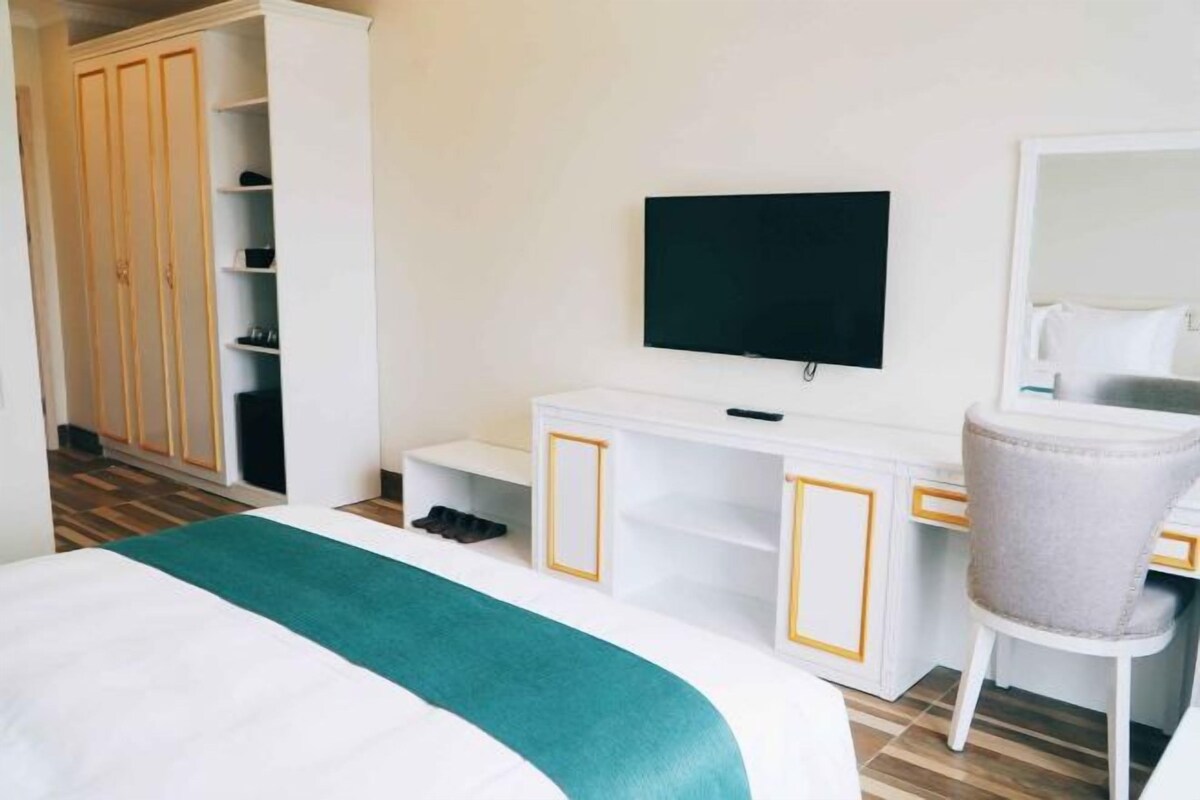 A hotel room with a bed, a desk, a TV, a wardrobe, and a chair.