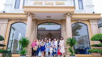 Un grupo de personas de pie frente a un edificio con un letrero que dice 'Minh Long Hotel'.