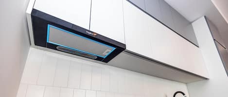 A modern kitchen with white cabinets, a black countertop, and a built-in range hood.