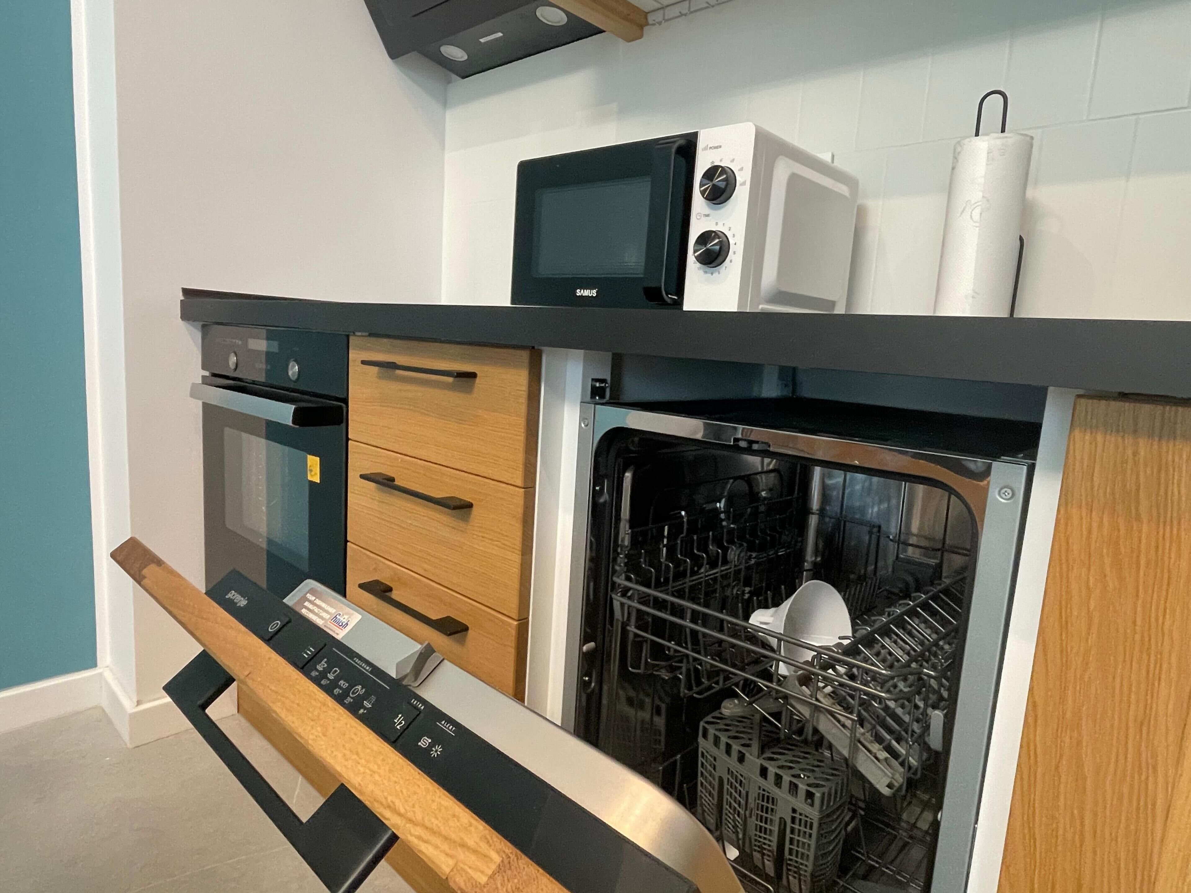 Cozinha compacta com micro-ondas, forno e máquina de lavar louça.