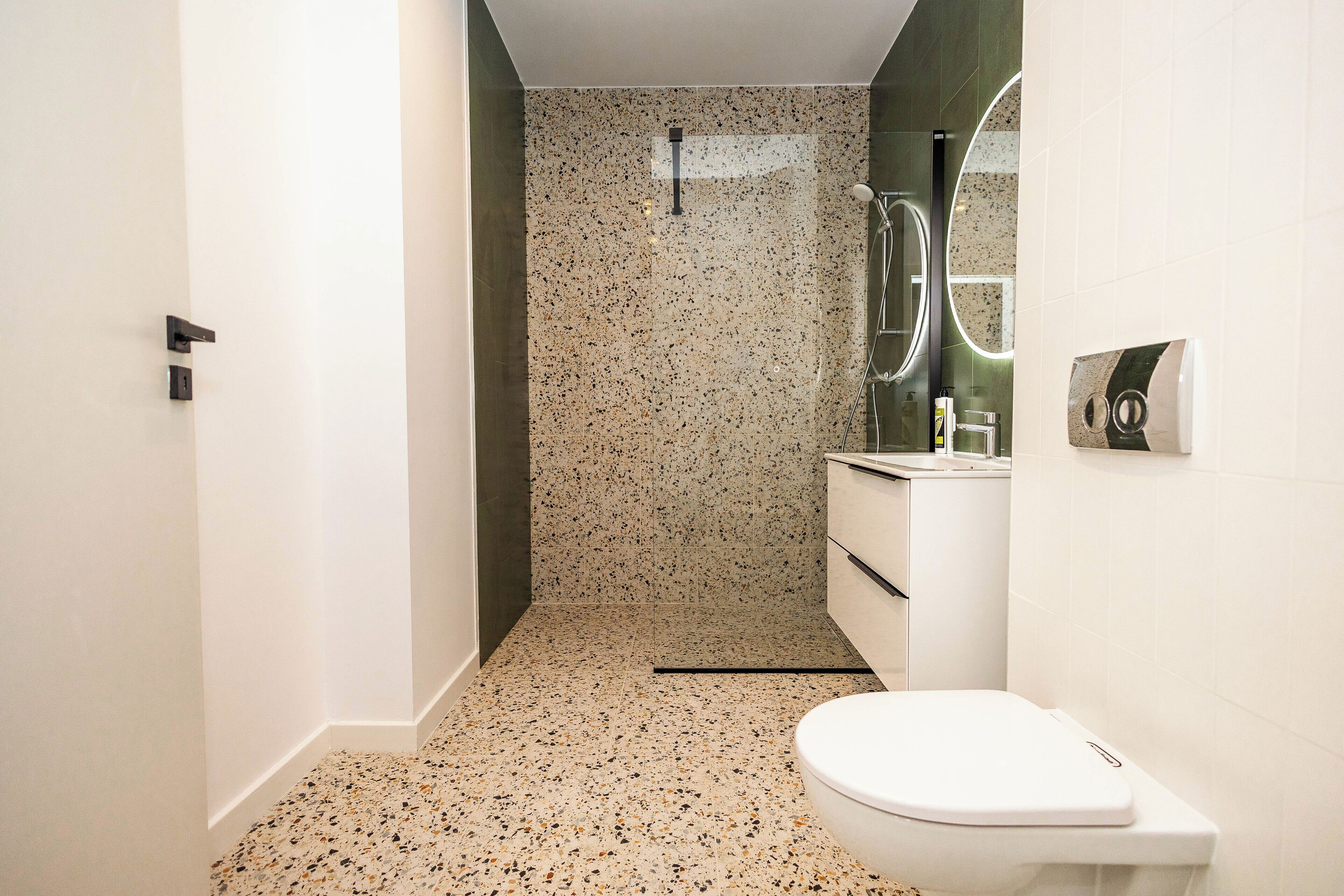 A modern bathroom with a white toilet, a sink, and a shower area.