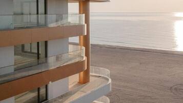 Un bâtiment moderne doté d’un balcon en verre donnant sur une plage.