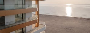 Een modern gebouw met een glazen balkon met uitzicht op een strand.