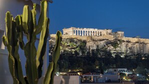 A historic building with columns and a cliff base, likely a tourist attraction.