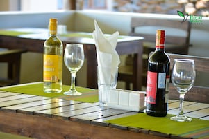 Una mesa con dos botellas de vino, dos copas de vino, una servilleta y un mantel individual.