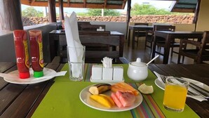 Ein Frühstücksbuffet mit Beilagen, einem Teller Essen, einem Glas Saft und einem Servietten auf einem Tisch.