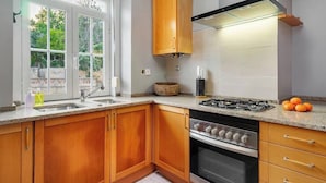 Una cocina con armarios de madera, una estufa a gas y un ventanal con vistas a la vegetación.