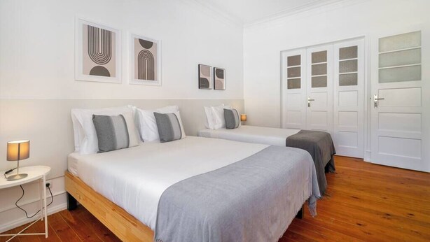 Una camera d'albergo con due letti, un comodino con lampada e un armadio con ante in vetro satinato.