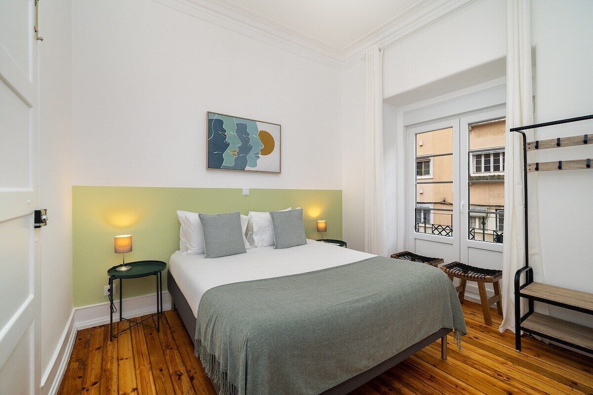 Ein Schlafzimmer mit einem Bett, zwei Nachttischen, einem Fenster mit Blick und einem Balkon.