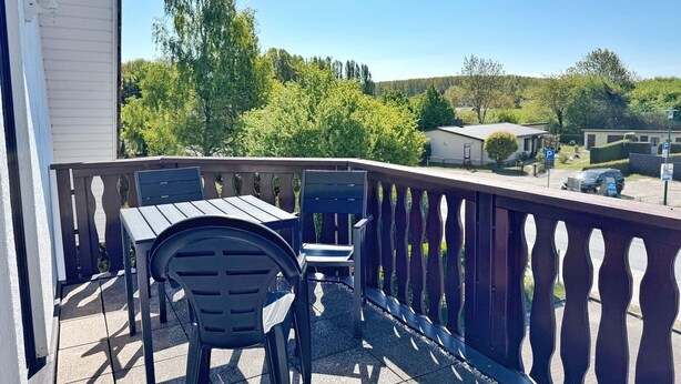 A balcony with a table and chairs, overlooking a residential area with houses and trees. - Baltique - Holiday apartment 3 Glowe - Holiday apartment Baltique 3 (Glowe)