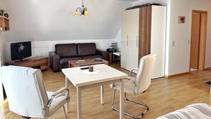 A modern living room with a sofa, a dining table, and a TV. - Baltique - Holiday apartment 3 Glowe - Holiday apartment Baltique 3 (Glowe)