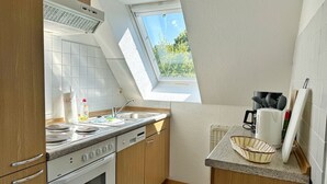A kitchen with a skylight, a stove, a sink, and wooden cabinets. - Baltique - Holiday apartment 3 Glowe - Holiday apartment Baltique 3 (Glowe)