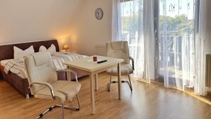 A modern hotel room with a sofa, two armchairs, a small table, and a large window with a view of the city. - Baltique - Holiday apartment 3 Glowe - Holiday apartment Baltique 3 (Glowe)