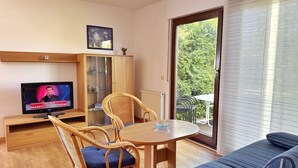 A living room with a television, wicker chairs, a round table, a sofa, and a glass cabinet. - Baltique - Holiday apartment 5 Glowe - Holiday apartment Baltique 5 (Glowe)