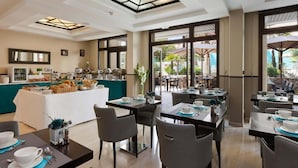 A hotel dining area with a buffet, tables set for dining, and a view of the outdoor patio. - Comfortable Room in Cannes for 2 Guests (Cannes)