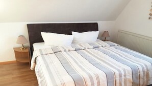A bedroom with a bed, two bedside lamps, and a radiator. - Baltique - Holiday apartment 4 Glowe - Holiday apartment Baltique 4 (Glowe)