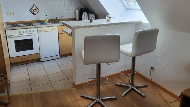 A kitchen with a stove, oven, and dishwasher, a small island with bar stools, and a skylight. - Baltique - Holiday apartment 4 Glowe - Holiday apartment Baltique 4 (Glowe)