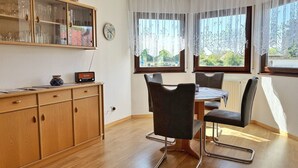 A dining area with a wooden cabinet, a clock, and a table with chairs. - Baltique - Holiday apartment 1 Glowe - Holiday apartment Baltique 1 (Glowe)