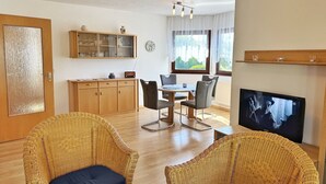 A living room with wicker furniture, a dining table, and a TV. - Baltique - Holiday apartment 1 Glowe - Holiday apartment Baltique 1 (Glowe)