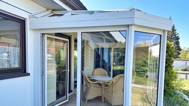 A corner conservatory with glass doors, wicker furniture, and a view of the garden. - Baltique - Holiday apartment 1 Glowe - Holiday apartment Baltique 1 (Glowe)