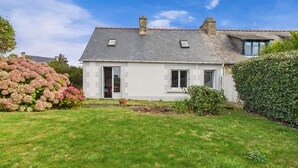 Une maison à deux étages avec un toit gris, une porte d’entrée et une petite fenêtre.