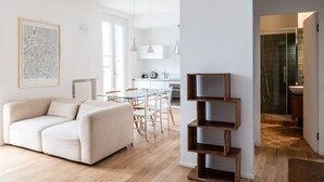 Un salon moderne comprenant un canapé, une table à manger, des chaises et une étagère en bois.