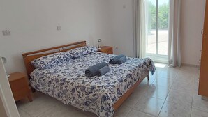 A bedroom with a bed, two nightstands, a window with curtains, and a view of the outside.