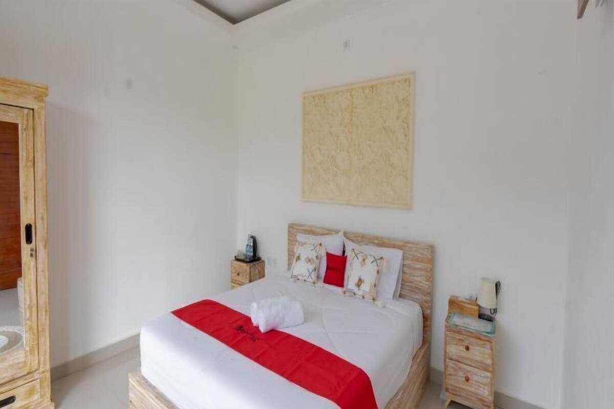 Een slaapkamer met een bed, een nachtkastje, een houten garderobe en een wanddecoratie.