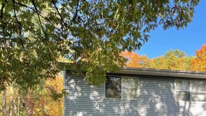 A two-story house with a balcony, a garage, and a small attached shed.