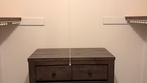 Un aparador de madera con cajones frente a una pared lisa, flanqueado por dos estantes blancos.