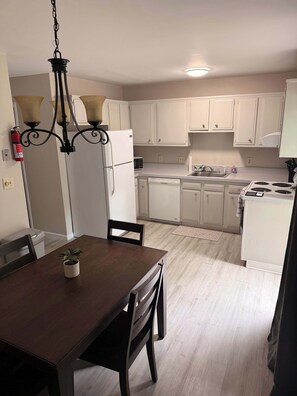 A kitchen with white cabinets, a microwave, a stove, and a dining area with a table and chairs.