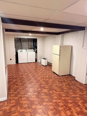 Une pièce dotée d’un parquet en bois, d’un lave-linge, d’un réfrigérateur et d’un chauffe-eau.