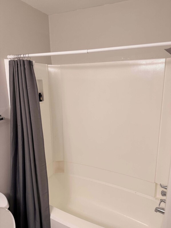 A bathroom with a bathtub, a shower curtain, and a toilet.