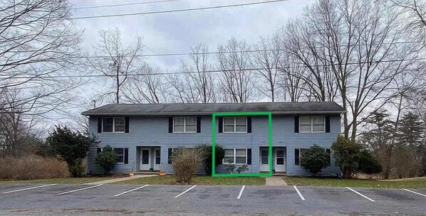 A two-story building with a flat roof, a front entrance, and a parking lot in front.