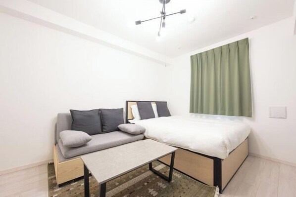 Une pièce de taille modeste comprenant un lit, un canapé et une petite table.