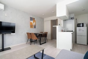 A modern kitchen with white appliances, a dining area with a table and chairs, and a flat-screen TV mounted on the wall. - aLATO Omorimachi (Tokyo)