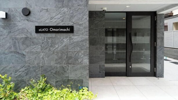 L'ingresso di un edificio moderno con un'insegna che riporta la scritta "aLATO Omorimachi".