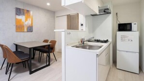 Una cucina compatta con lavandino, fornello e microonde, e un'area pranzo con tavolo e sedie.