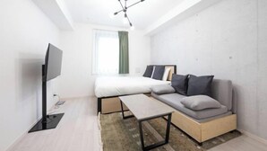 Camera da letto moderna e minimalista con un letto, un divano, una TV e una luce a soffitto.