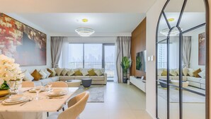 A modern living room with a sofa set, dining area, and a large mirror reflecting the room. - Downtown Views Residences - Downtown DXB (Dubai)