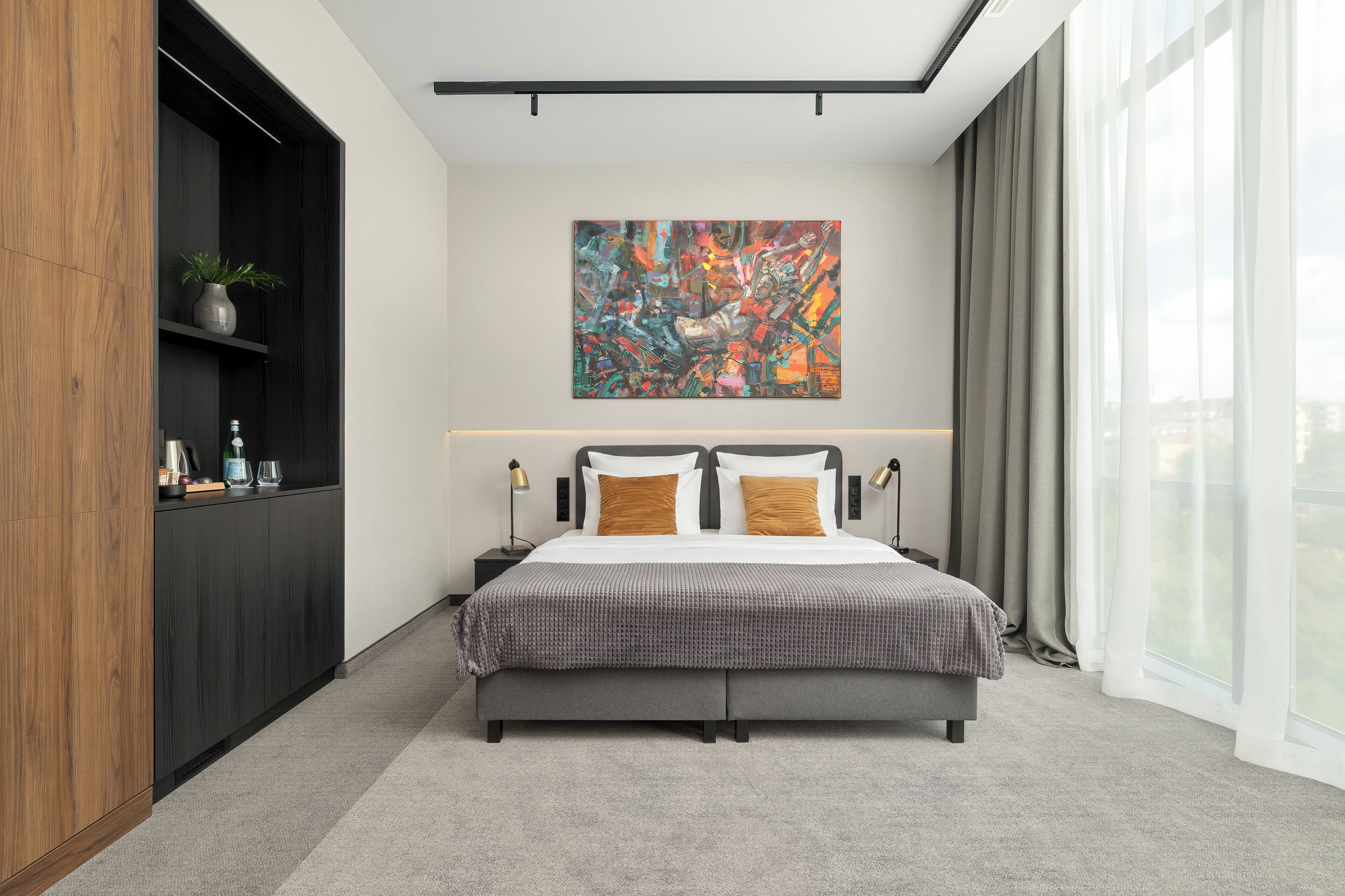 A modern bedroom with a large bed, a nightstand, a wall-mounted abstract painting, and a large window with curtains.