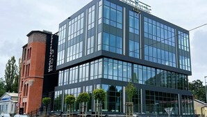 A modern building with a glass facade, a prominent sign reading "Westraillic City," and a brick structure to the left.