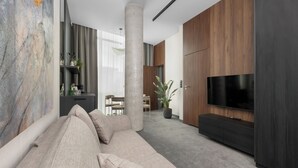 A modern living room with a sofa, TV, and wooden panel walls.